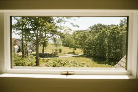 A garden and trees seen through an open white window frame