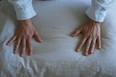 Two hands pressing flat on a soft linen pillow