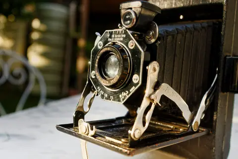 Vintage folding camera with its bellows open on a sunlit table